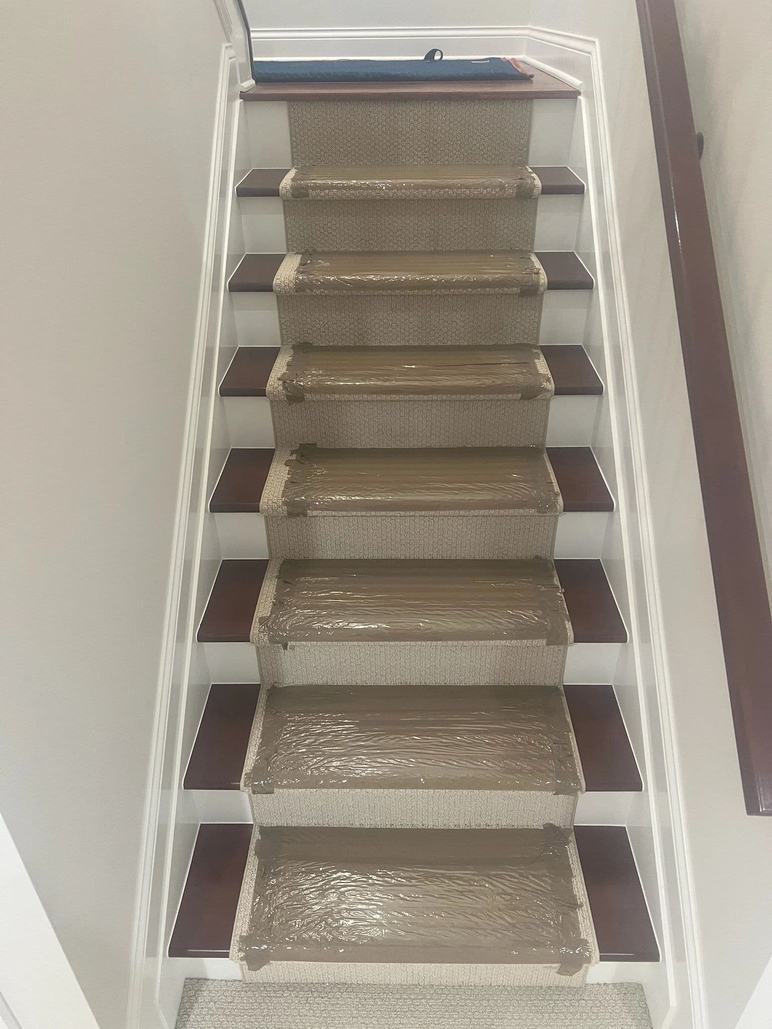 Staircase prepped for moving day — every carpeted tread wrapped in taped protective film