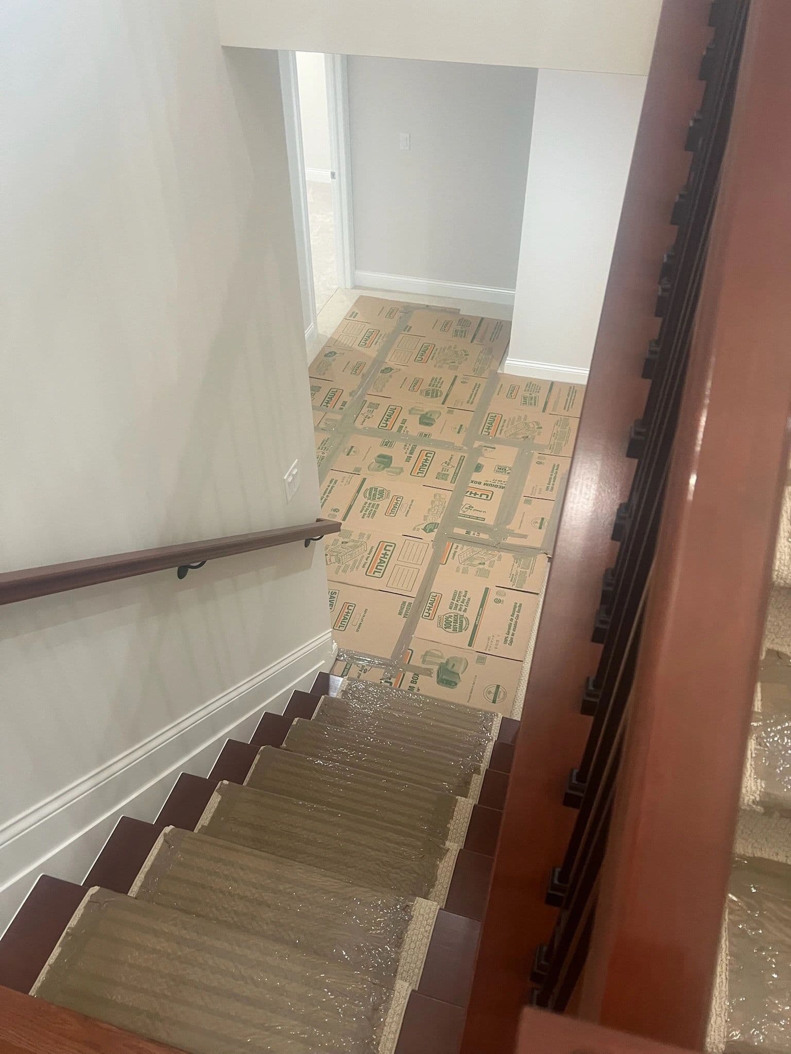Looking down a protected staircase to a landing floored edge-to-edge with taped-down cardboard