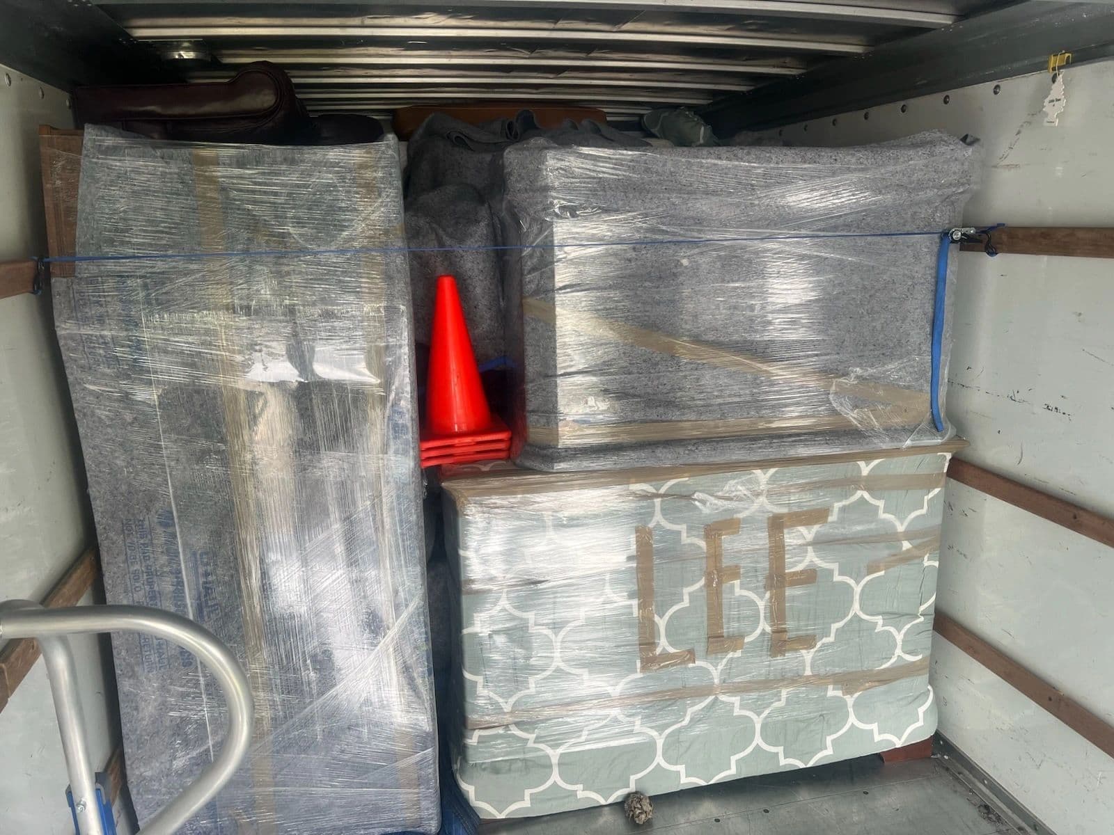 Inside the truck: furniture wrapped in moving blankets and stretch wrap, strapped and loaded tight