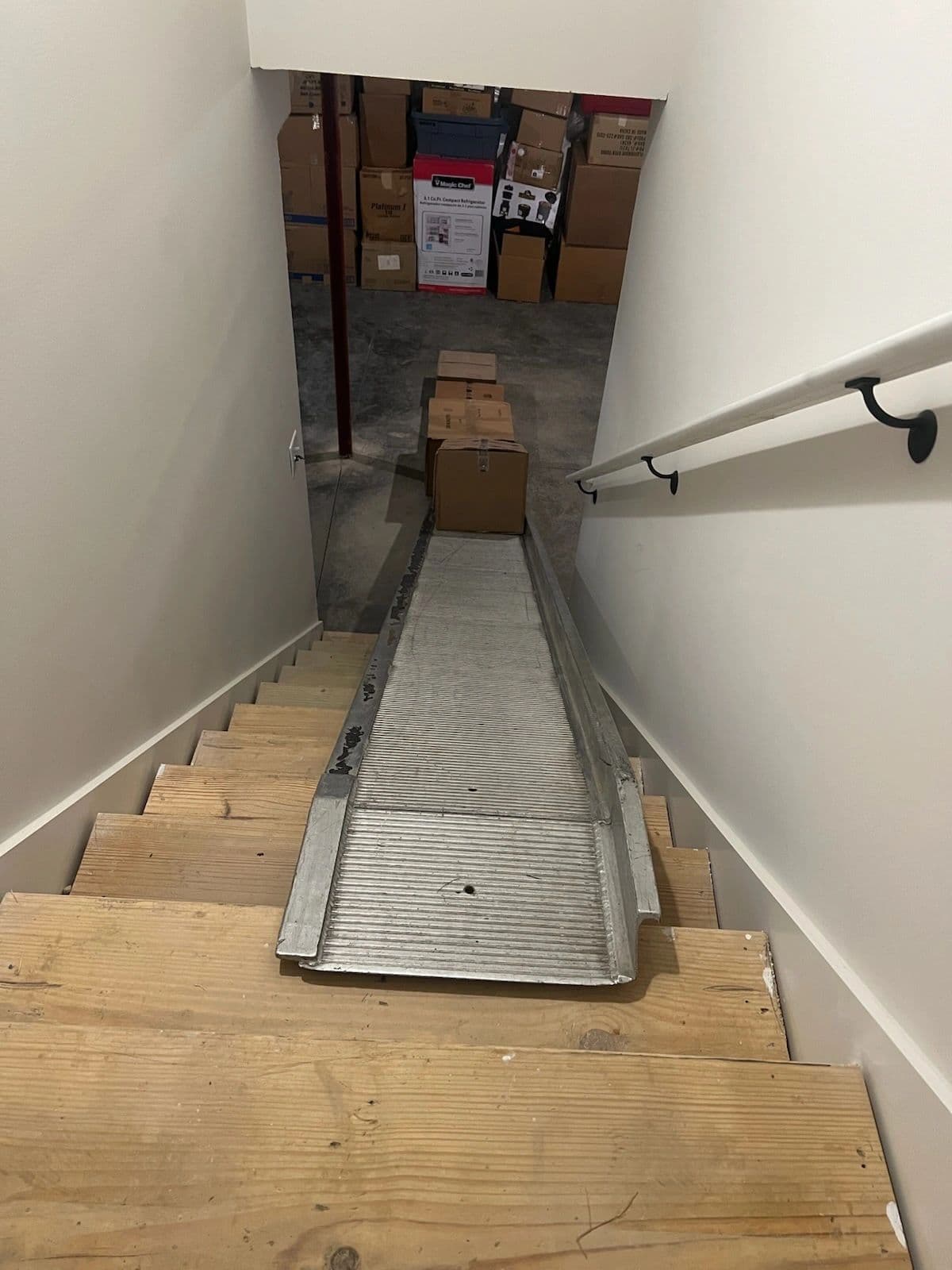 Aluminum walk ramp laid over basement stairs for a safe carry down