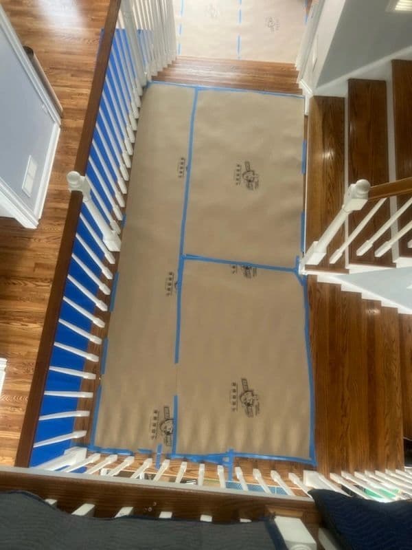 Foyer hardwood fully masked with taped paper floor protection between two staircases